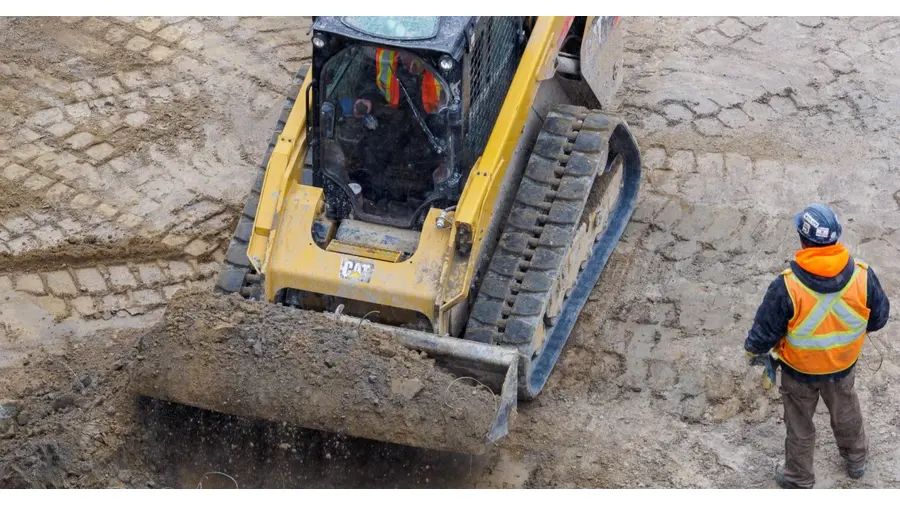 Top view of a bulldozer and worker on a construction site preparing the ground.