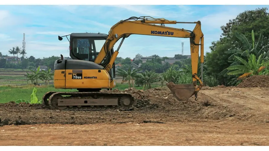 Yellow excavator on a rural construction site on a sunny day.