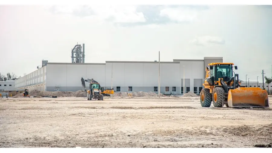 A large construction site featuring heavy machinery and industrial building in progress.